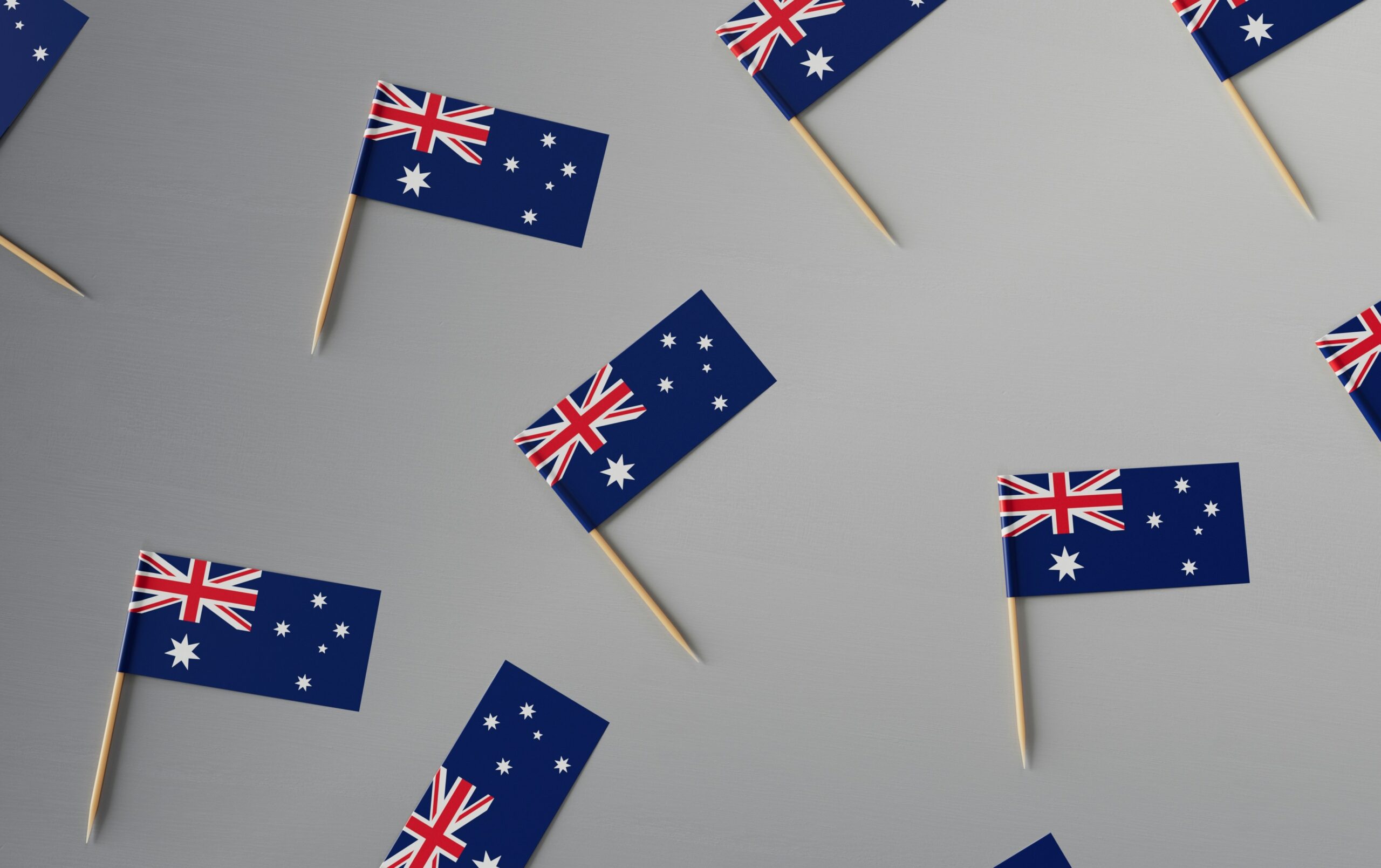 several cocktail sized Australian flags on a grey background